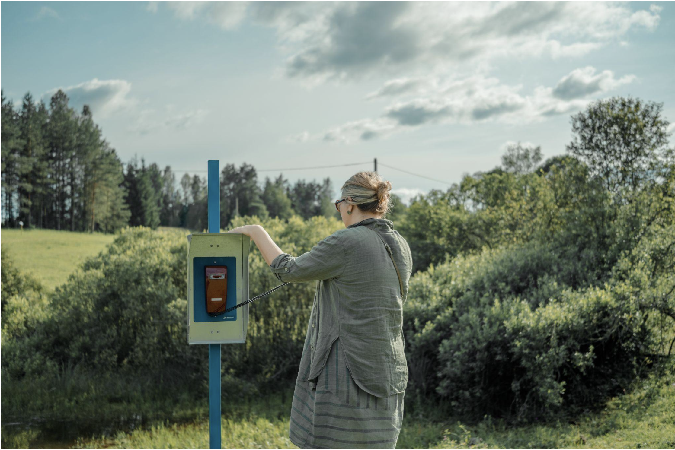 A visitor with a hand on the Nephophile that observes the sky's reflection in the pond. Maajaam, Estonia, July 2025. Photo by Ya Chuan Chen