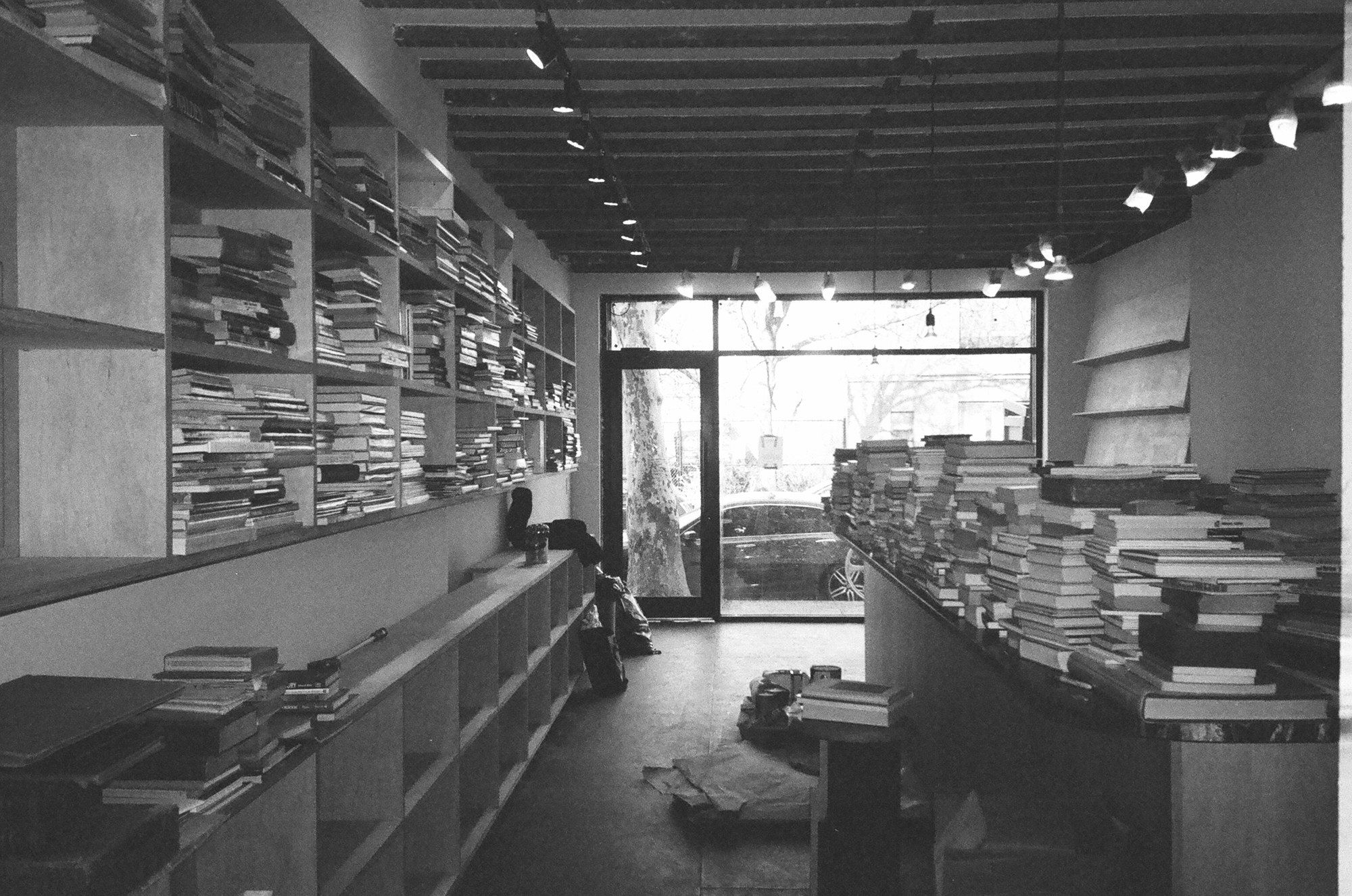 Black-and-white photograph of the Dear Friend interior with stacks of books.