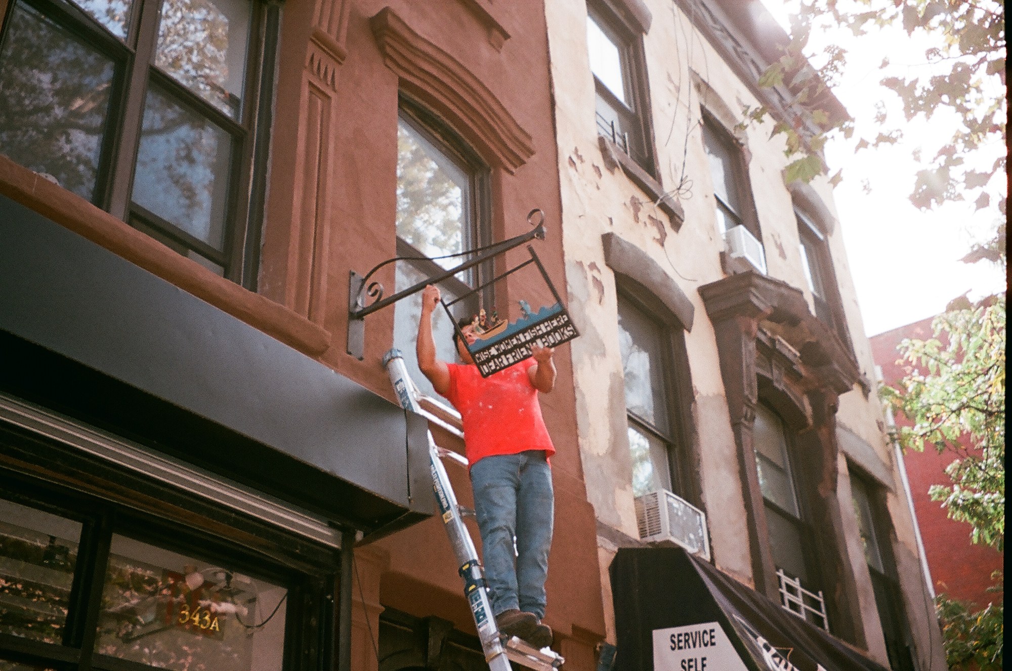A person installing a sign outside Dear Friend.